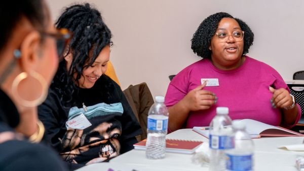 Black women converse around workshop table