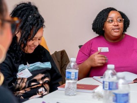 Black women converse around workshop table