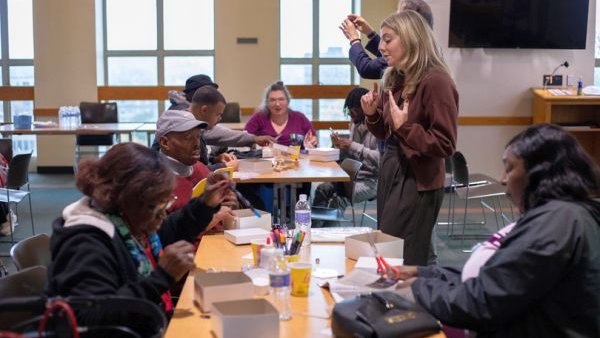 several people standing and seated around a work table
