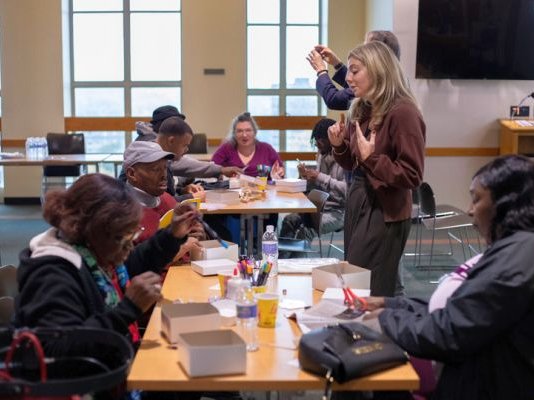 several people standing and seated around a work table