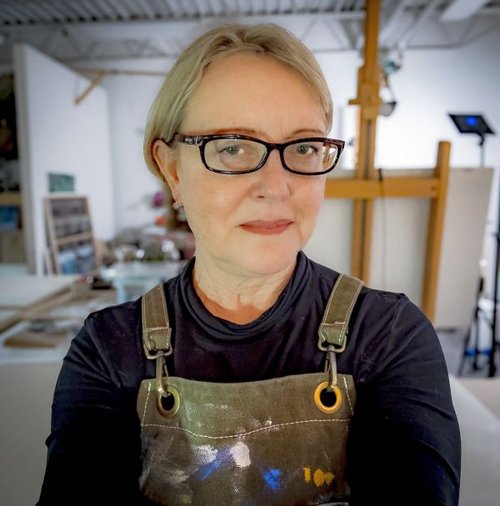Linda Infante Lyons poses in painter&#x27;s studio wearing artist&#x27;s smock