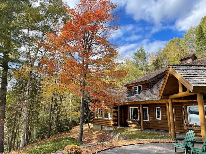 view of rustic cabin beyond fall-colored trees
