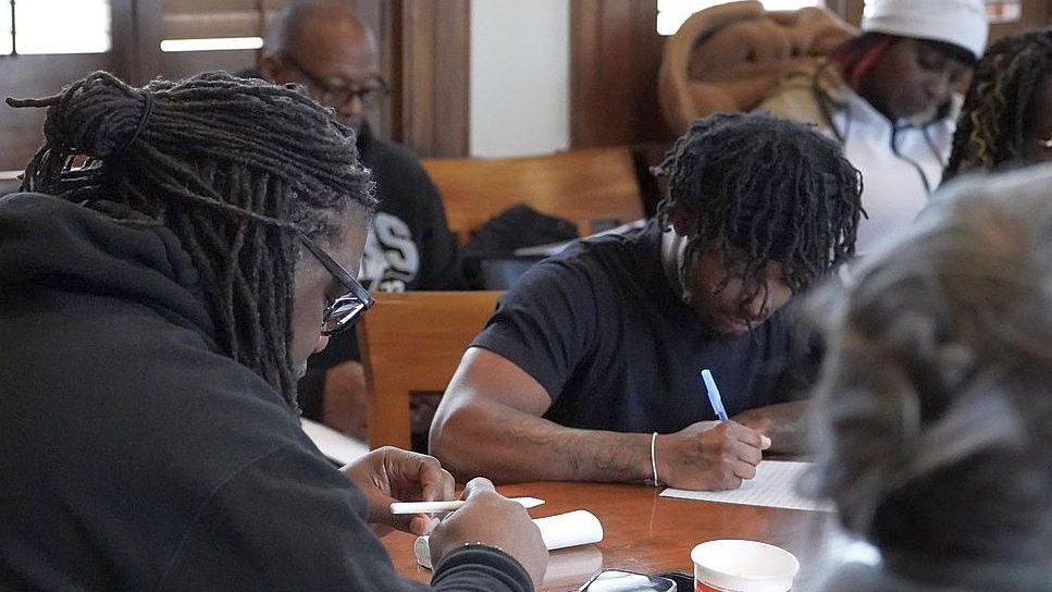 writers hunker down at a table with their pens and paper