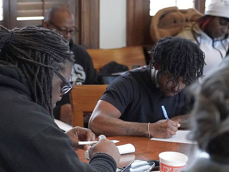 writers hunker down at a table with their pens and paper